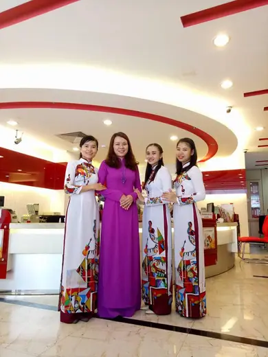 Bốn phụ nữ mặc áo dài trong sảnh ngân hàng, một người mặc áo tím.