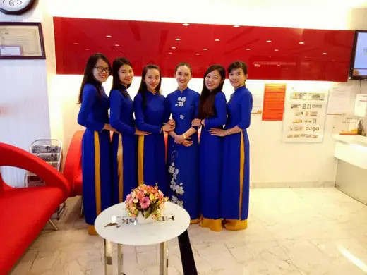 Sáu nữ nhân viên mặc áo dài đồng phục xanh dương đứng trong sảnh giao dịch.