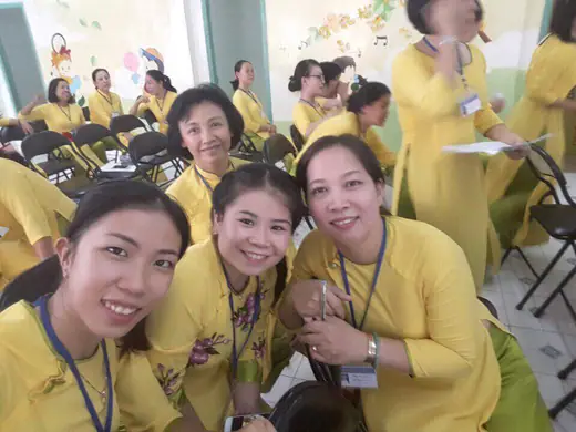 Nhóm cô giáo mặc áo dài vàng chụp ảnh tự sướng trong hội trường.