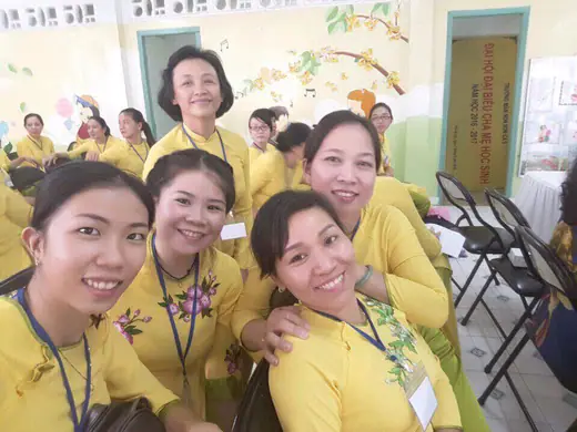 Nhóm cô giáo mặc áo dài vàng chụp ảnh tự sướng trong lớp học.