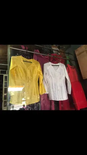 Ba chiếc áo bà ba vàng, trắng, đỏ treo trên móc.