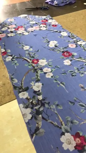 Vải xanh tím nhạt in hoa trải trên bàn cắt.