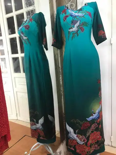 Hai chiếc áo dài xanh ngọc cổ vuông thêu chim hạc trên ma-nơ-canh.