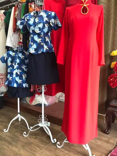 Áo dài đỏ cạnh bộ áo váy xanh in chim hạc cho mẹ và bé trên ma-nơ-canh.