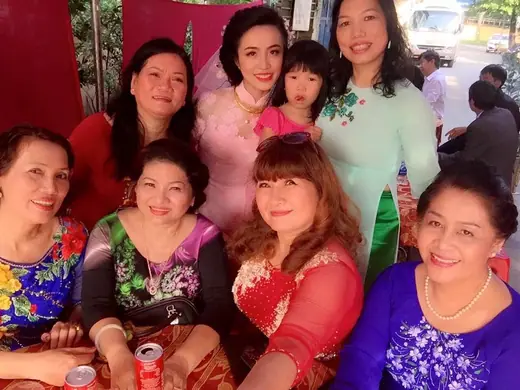 Nhóm phụ nữ mặc áo dài nhiều màu chụp chung trong tiệc cưới.