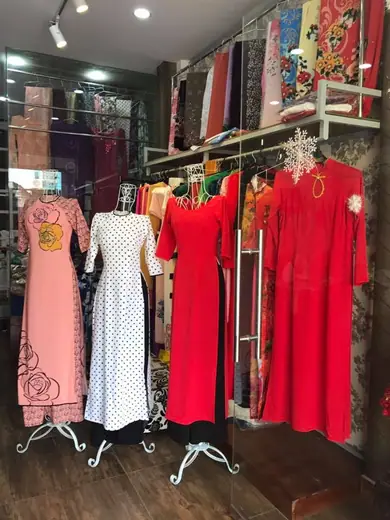 Bốn chiếc áo dài trên ma-nơ-canh trong tiệm: hồng vẽ hoa, trắng chấm bi, đỏ và đỏ ren.