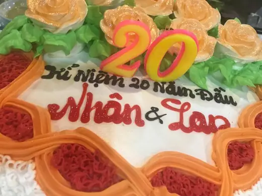 Bánh kem trang trí hoa có số 20 và dòng chữ kỷ niệm 20 năm.