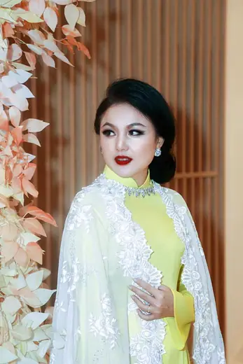 Chân dung một phụ nữ mặc áo dài vàng chanh khoác áo choàng ren trắng.