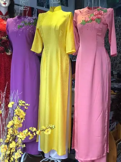 Ba chiếc áo dài tím, vàng và hồng đính hoa nổi trên ma-nơ-canh.