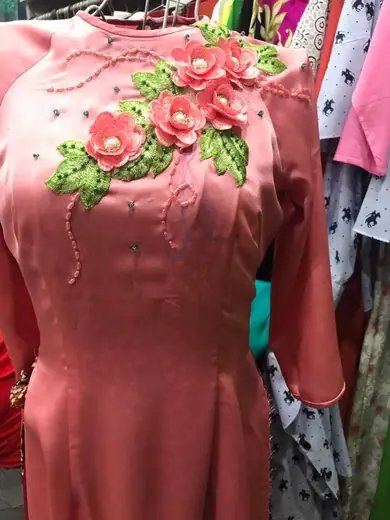 Cận cảnh áo dài hồng đất đính hoa vải nổi ở ngực áo.