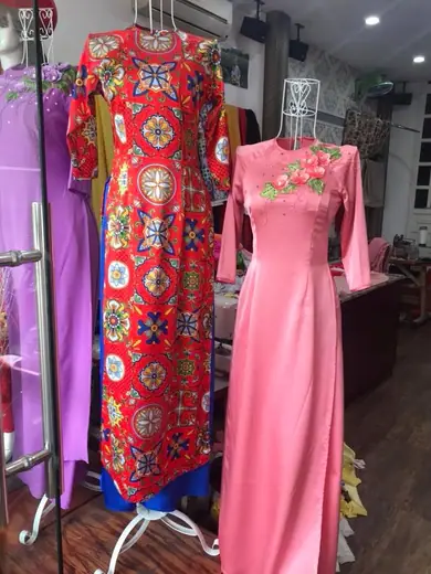 Áo dài gấm đỏ hoạ tiết và áo dài hồng trên ma-nơ-canh.