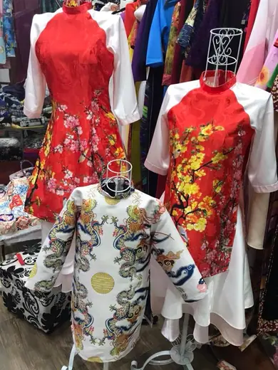 Các mẫu áo cách tân đỏ in hoa mai phối tay trắng và áo trẻ em in hình rồng trên ma-nơ-canh.