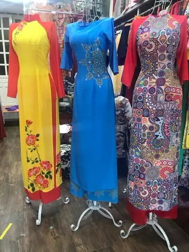 Ba chiếc áo dài vàng, xanh dương và hoạ tiết nhiều màu trên ma-nơ-canh.
