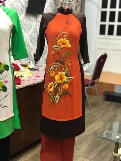 Áo cách tân cam vẽ hoa vàng phối đen trên ma-nơ-canh.