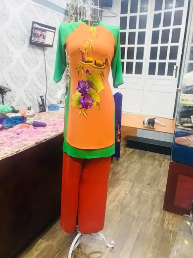 Bộ áo cách tân cam phối xanh lá vẽ hoa tím cùng quần cam trên ma-nơ-canh.