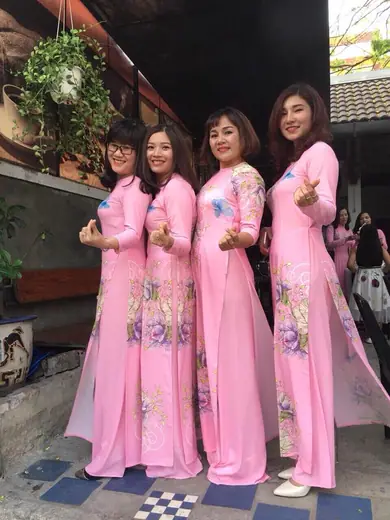 Bốn phụ nữ mặc áo dài đồng phục hồng in hoa tạo dáng.
