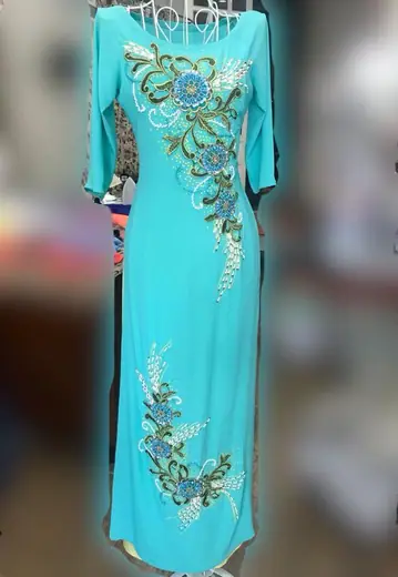 Áo dài xanh ngọc kết cườm hình hoa treo trên móc.