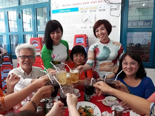 Nhóm thầy cô nâng ly chúc mừng bên bàn tiệc.
