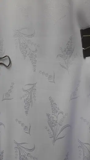 Cận cảnh vải trắng dệt hoa văn cành lá.