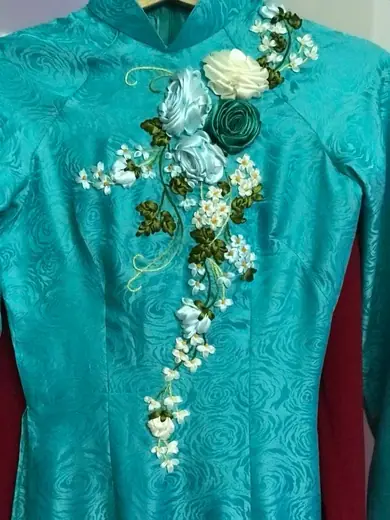 Áo dài xanh ngọc đính hoa ruy băng trên ma-nơ-canh.