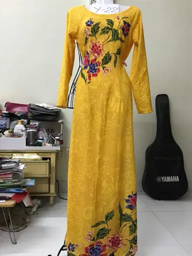Áo dài lụa vàng in hoa may sẵn trên ma-nơ-canh.