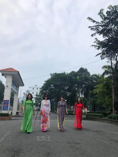 Nhóm phụ nữ mặc áo dài đi trên sân.
