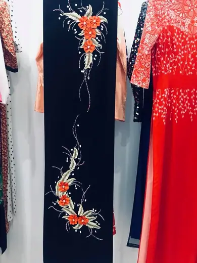 Áo dài nhung xanh đen thêu hoa cam và áo dài đỏ kết cườm trên ma-nơ-canh.