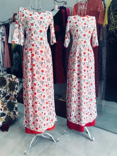 Hai chiếc áo dài đồng phục trắng in hoa đỏ trên ma-nơ-canh.
