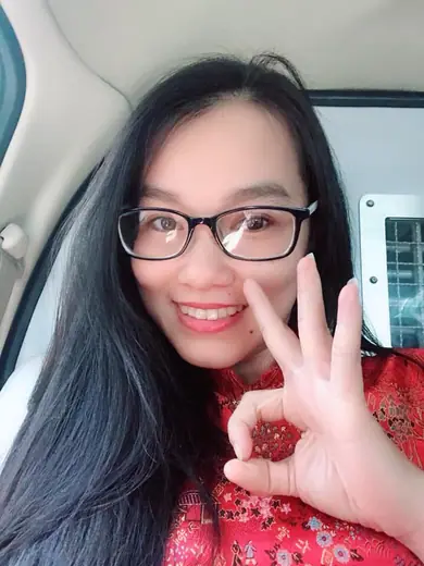 Ảnh tự chụp của một phụ nữ đeo kính mặc áo dài ren đỏ ngồi trong xe.