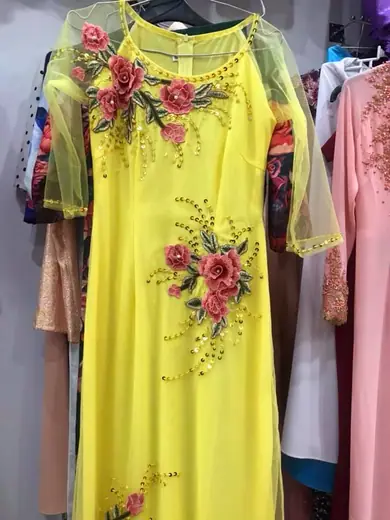 Áo dài vàng tay voan đính hoa đỏ nổi treo trên móc.