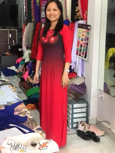 Một phụ nữ mặc áo dài đỏ chuyển đen tươi cười trong tiệm.