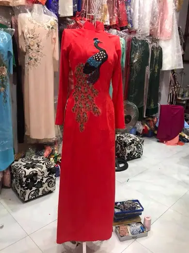 Áo dài đỏ kết cườm hình chim công trên ma-nơ-canh trong tiệm.