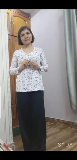 Một phụ nữ mặc áo bà ba trắng hoa nhí và quần đen.