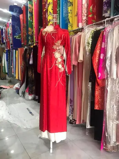 Áo dài đỏ đính hoa vải nổi trên ma-nơ-canh trong tiệm.