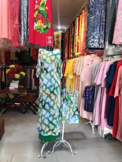 Áo dài kẻ ô xanh lá vẽ hoa cùng chiếc váy bé gái đồng bộ trên ma-nơ-canh.