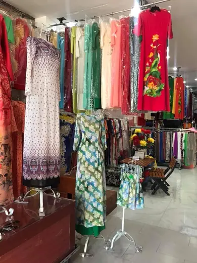 Áo dài kẻ ô xanh và váy bé gái đồng bộ giữa tiệm.