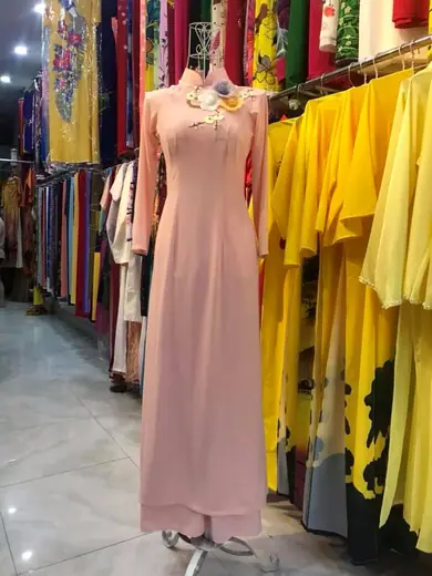 Áo dài hồng phấn đính hoa nổi ở cổ trên ma-nơ-canh.