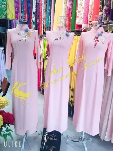 Ba chiếc áo dài hồng phấn tay liền đính hoa trên ma-nơ-canh.