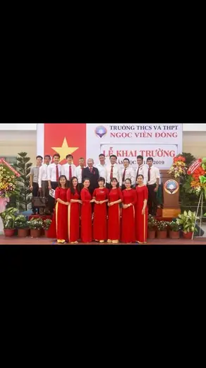 Tập thể giáo viên mặc áo dài đỏ trên sân khấu lễ khai giảng.