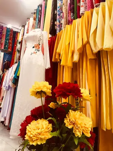 Áo dài trắng thêu hoa đỏ trên ma-nơ-canh trong tiệm.