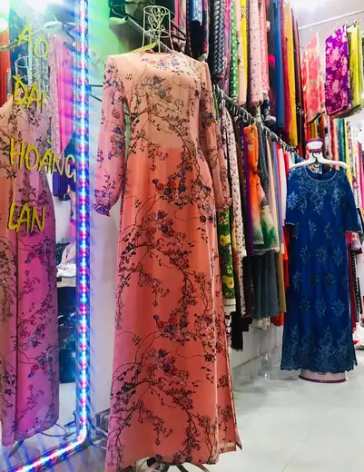 Áo dài màu cam đất in hoa dây leo trên ma-nơ-canh, ảnh có chữ tên tiệm.