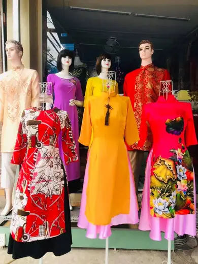 Các ma-nơ-canh trước tiệm mặc áo dài cách tân đỏ, vàng và hồng đón Tết.