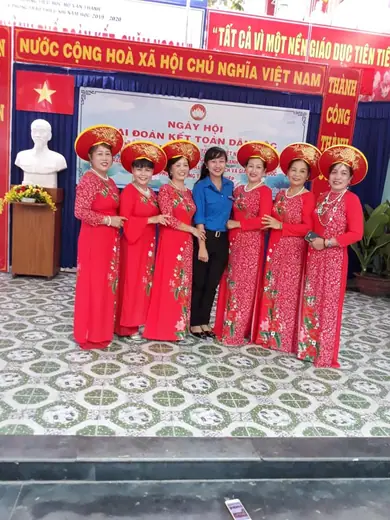 Nhóm hội viên phụ nữ mặc áo dài đỏ hồng, đội mấn, chụp chung tại ngày hội đại đoàn kết.
