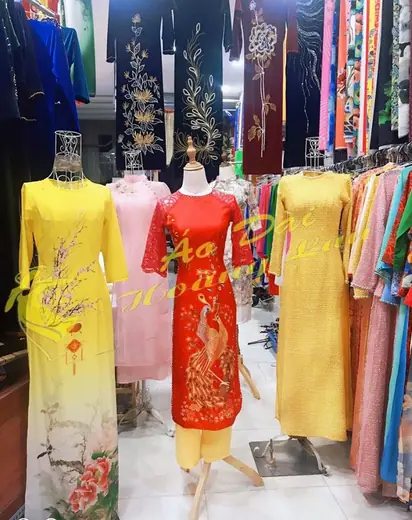 Các ma-nơ-canh trong tiệm mặc áo dài vàng in hoa mai, áo dài đỏ in chim phượng và áo dài ren.