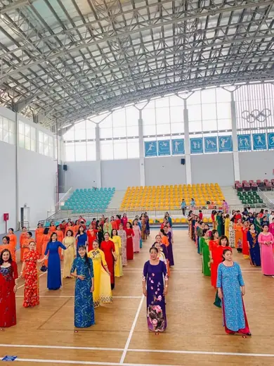 Đông đảo phụ nữ mặc áo dài nhiều màu đồng diễn trong nhà thi đấu.