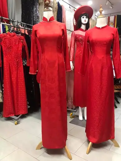 Ba chiếc áo dài cưới đỏ trên ma-nơ-canh, một chiếc đội mấn.
