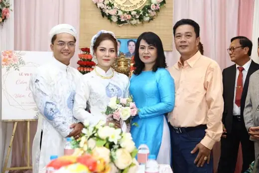Cô dâu chú rể mặc áo dài trắng chụp cùng cha mẹ.
