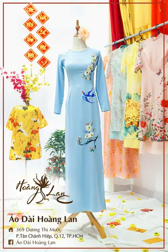 Áo dài xanh nhạt thêu chim én và áo trẻ em vàng in hoa, khung ảnh có tên tiệm.