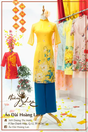Áo dài cách tân vàng vẽ hoa phối quần xanh cổ vịt và áo trẻ em đỏ, khung ảnh có tên tiệm.