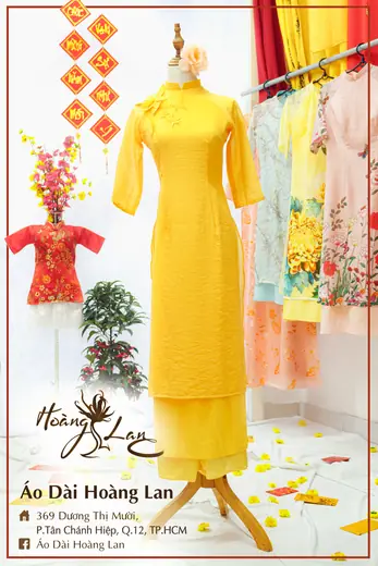 Áo dài cách tân vàng phối quần vàng và áo trẻ em đỏ, khung ảnh có tên tiệm.